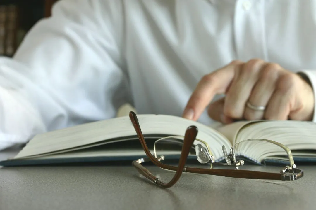 Una persona leyendo mientras señala con el dedo el renglón del libro