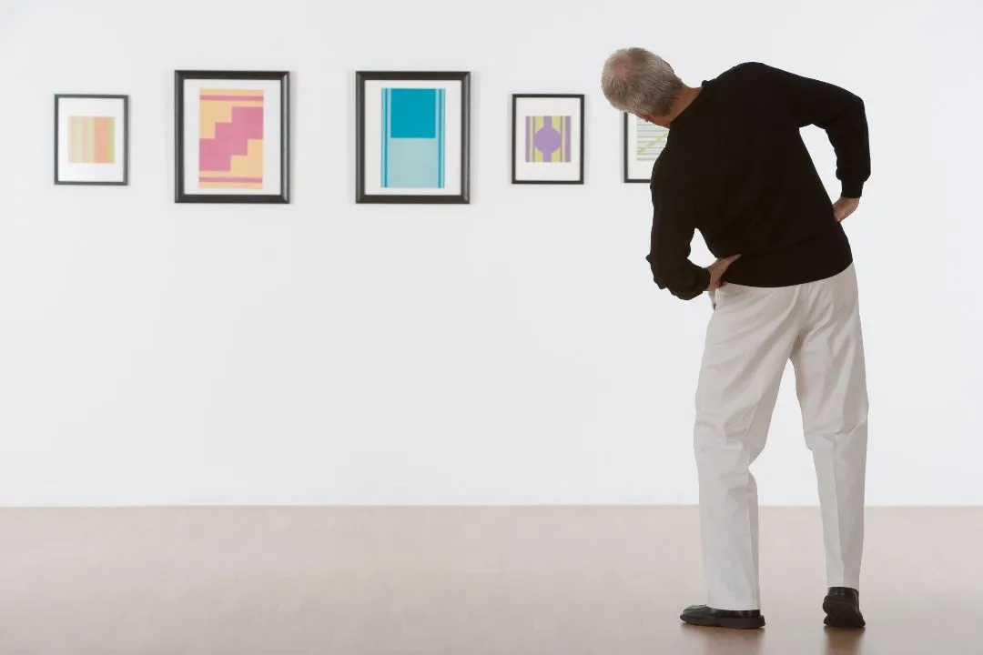 Hombre de espaldas mirando un cuadro de una galería